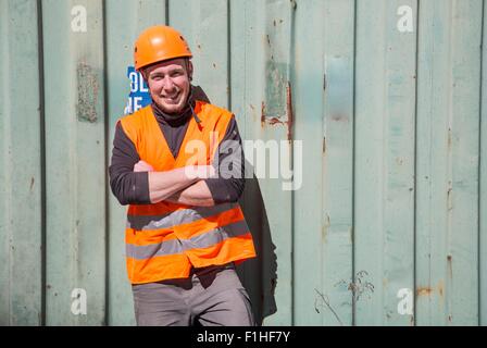 Portrait of worker wearing protective workwear in front of wooden door Stock Photo
