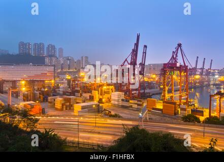 Cargo containers and loading cranes illuminated at night, Hong Kong, China Stock Photo