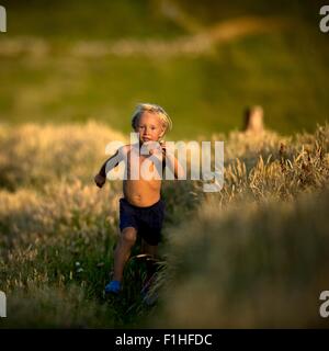 Young boy running through field Stock Photo