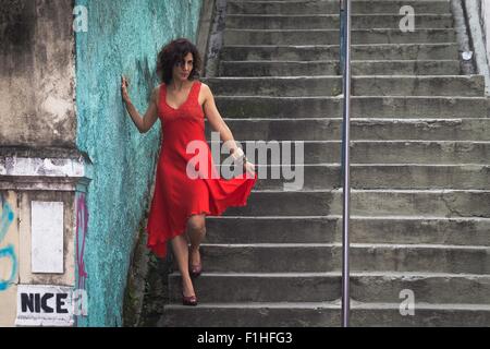 Fashion model wearing red dress walking down steps Stock Photo