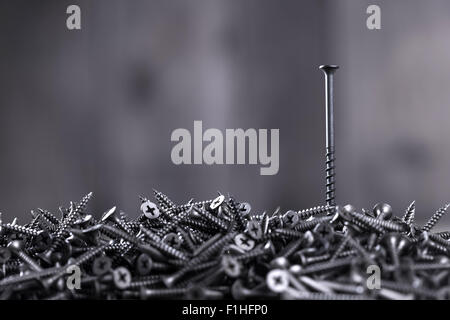 Pile of black screws closeup on wooden background Stock Photo