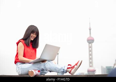 Young woman using laptop, outdoors, Shanghai, China Stock Photo