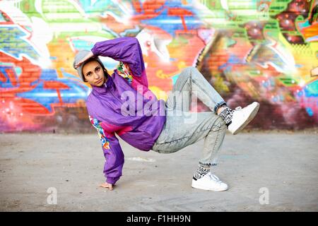 Young woman breakdancing freeze against graffiti Stock Photo