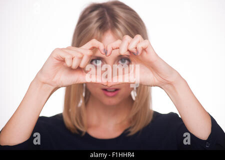 Blonde woman making a heart shape with her hands Stock Photo