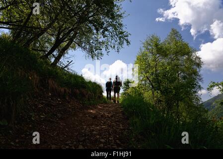 Silhouetted view of mature male and female hikers hiking up path Stock Photo