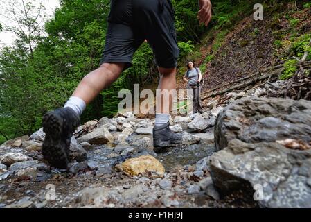 Waist down rear view of mature male hiker hiking in stream Stock Photo