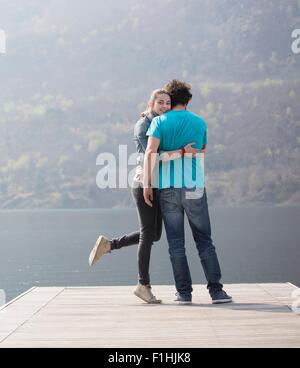 Young couple standing hugging on pier at Lake Mergozzo, Verbania, Piemonte, Italy Stock Photo