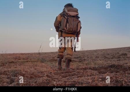 Mid adult man walking through field, rear view, low angle view Stock Photo