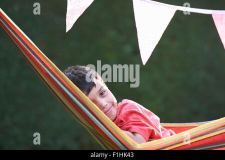 Portrait of cute boy reclining in striped garden hammock Stock Photo