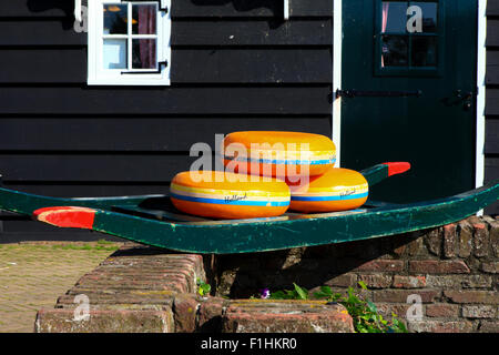 Dutch Cheese wheels on a green cart with farm house in the background Stock Photo