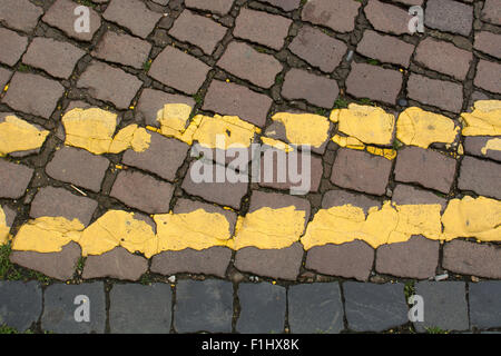 Double yellow lines on a cobbled road surface, UK Stock Photo
