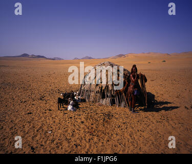 Portrait Himba Woman Standing near Hut with Goats, Namibia, Africa Stock Photo