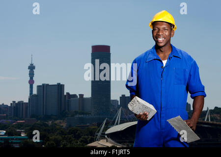 Construction worker laying bricks with cityscape in background Stock Photo