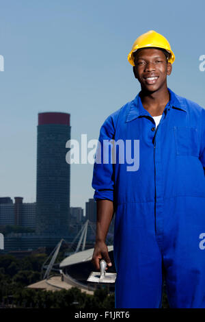 Construction worker laying bricks with cityscape in background Stock Photo