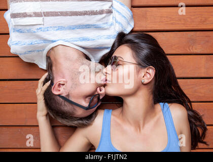 Happy young couple lying head to head on a wooden floor