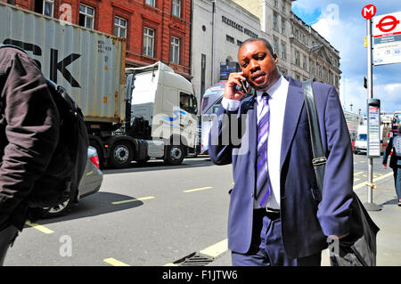 London, England, UK. Black businessman in the street talking on his mobile phone Stock Photo