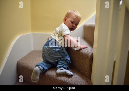 A one year old child climbing (up-down) the stairs in her home. Stock Photo