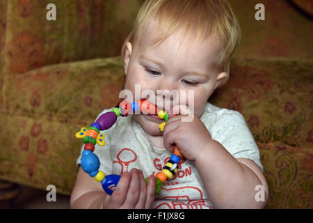 A teething eleven month old baby biting on a teething ring to alleviate the pain and discomfort of tooth ache. Stock Photo
