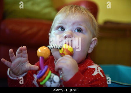 A teething eleven month old baby biting on a teething ring to alleviate the pain and discomfort of tooth ache. Stock Photo