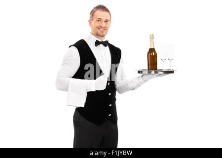 Cheerful male waiter with a bow-tie and black vest holding a tray with a champagne and two empty glasses on it Stock Photo