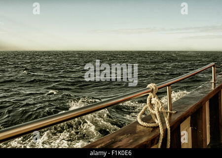 A wooden ship with a wet deck sailing on a bumpy sea Stock Photo