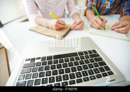 Laptop keypad on desk and two college students making notes Stock Photo