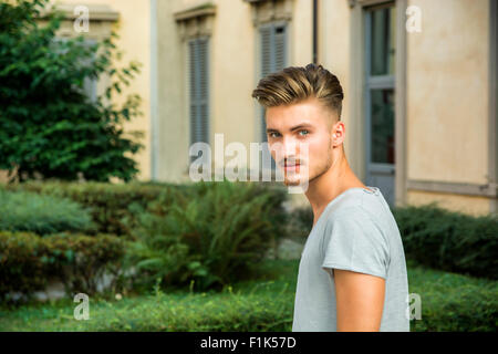 Handsome young man standing outdoors under old colonnade in european town Stock Photo