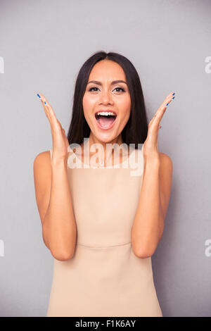 Young woman in dress screaming over gray background and looking at camera Stock Photo