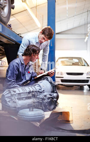 Mechanic with clipboard talking to customer in auto repair shop Stock Photo