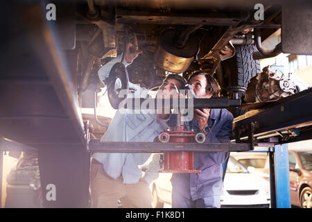 Mechanic and customer under car in auto repair shop Stock Photo