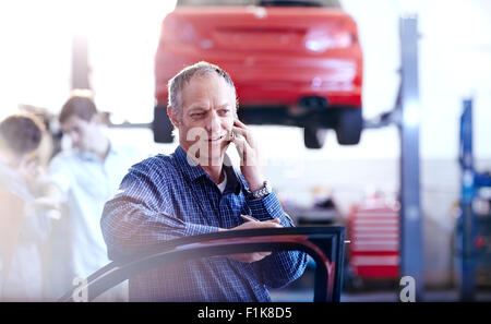 Man talking on cell phone in auto repair shop Stock Photo