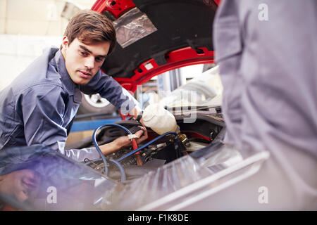 Mechanic working on car engine in auto repair shop Stock Photo