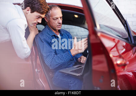 Mechanics with laptop at car in auto repair shop Stock Photo