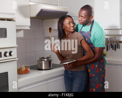 Couple embracing in kitchen while cooking Stock Photo