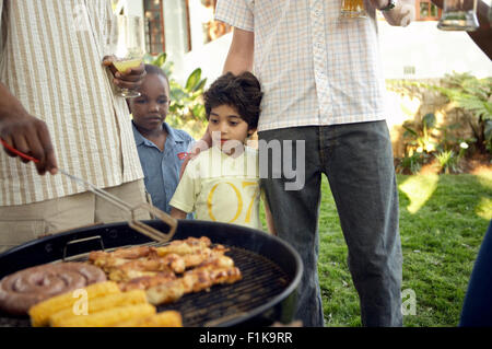 Multicultural group of friends having a braai/barbecue, two boys watching the fire, South Africa Stock Photo