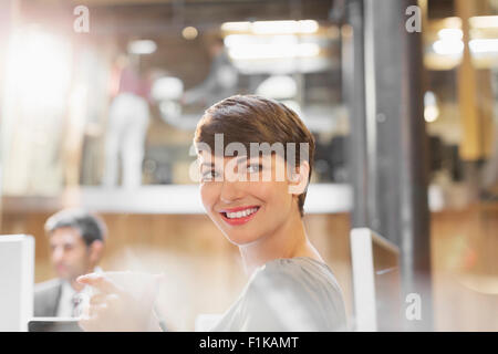 Smiling businesswoman drinking coffee in office Stock Photo