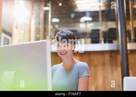 Portrait smiling businesswoman working at computer in office Stock Photo