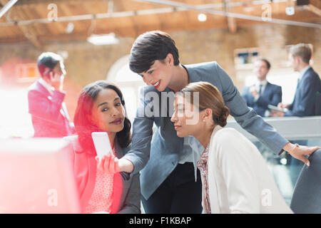 Businesswomen texting with cell phone in office Stock Photo