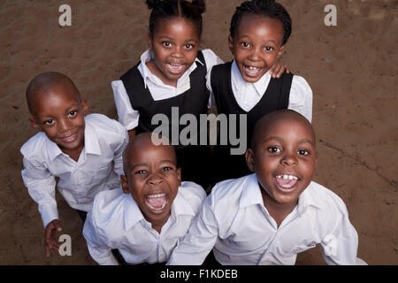 Group of African schoolchildren stand in a school playground, smiling at camera Stock Photo