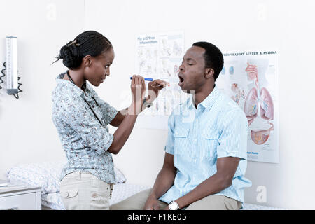 Female African doctor examining young African man Stock Photo