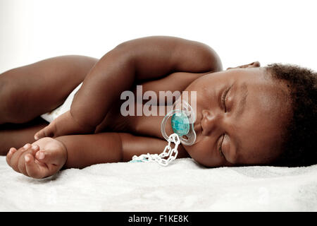 An infant sleeping with a dummy in his mouth Stock Photo