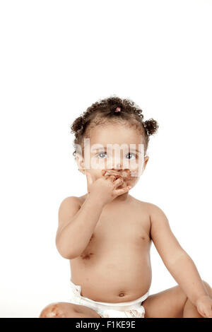 An infant sits in front of a white background with chocolate all over her face Stock Photo