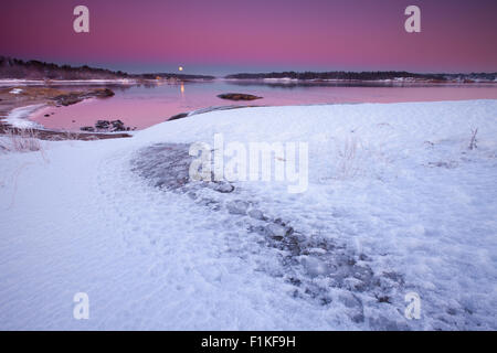 Winter evening with colorful skies, rising moon, and earth shadow. By the Oslofjord, at Oven in Råde, Østfold Norway. Stock Photo