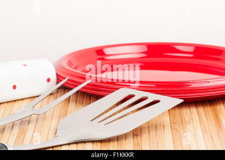 A set of barbecue tools and plastic plates on a bamboo mat symbolizing barbecue time. Stock Photo