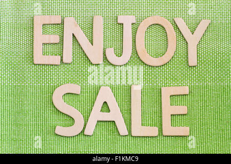 Enjoy sale written with wooden letters on green surface Stock Photo
