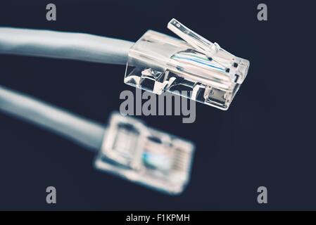 Network Cable Grey Cord with Connector RJ45 on Dark Blue Background Stock Photo