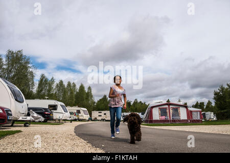 Girl running with her dog in a caravan park, Peak District, UK Stock Photo