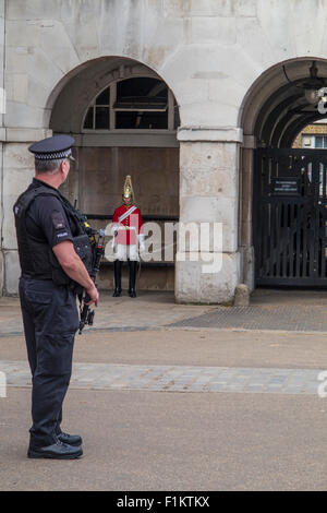 A policeman with an automatic rifle stands near a household cavalry guard with a sword at Whitehall Stock Photo