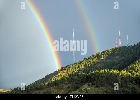 Double Rainbow Over the Mountain with Broadcast Antennas. Colorful Summer Rainbow. Stock Photo