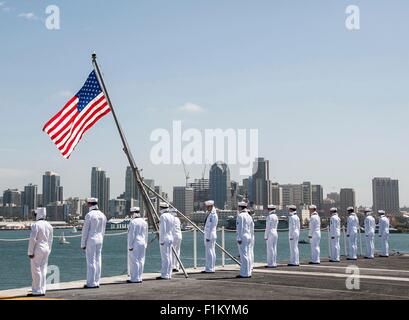 U.S. Navy Sailors man the rails on the flight deck of the Nimitz-class aircraft carrier USS Ronald Reagan as it departs for Japan August 31, 2015 in San Diego, California. Stock Photo